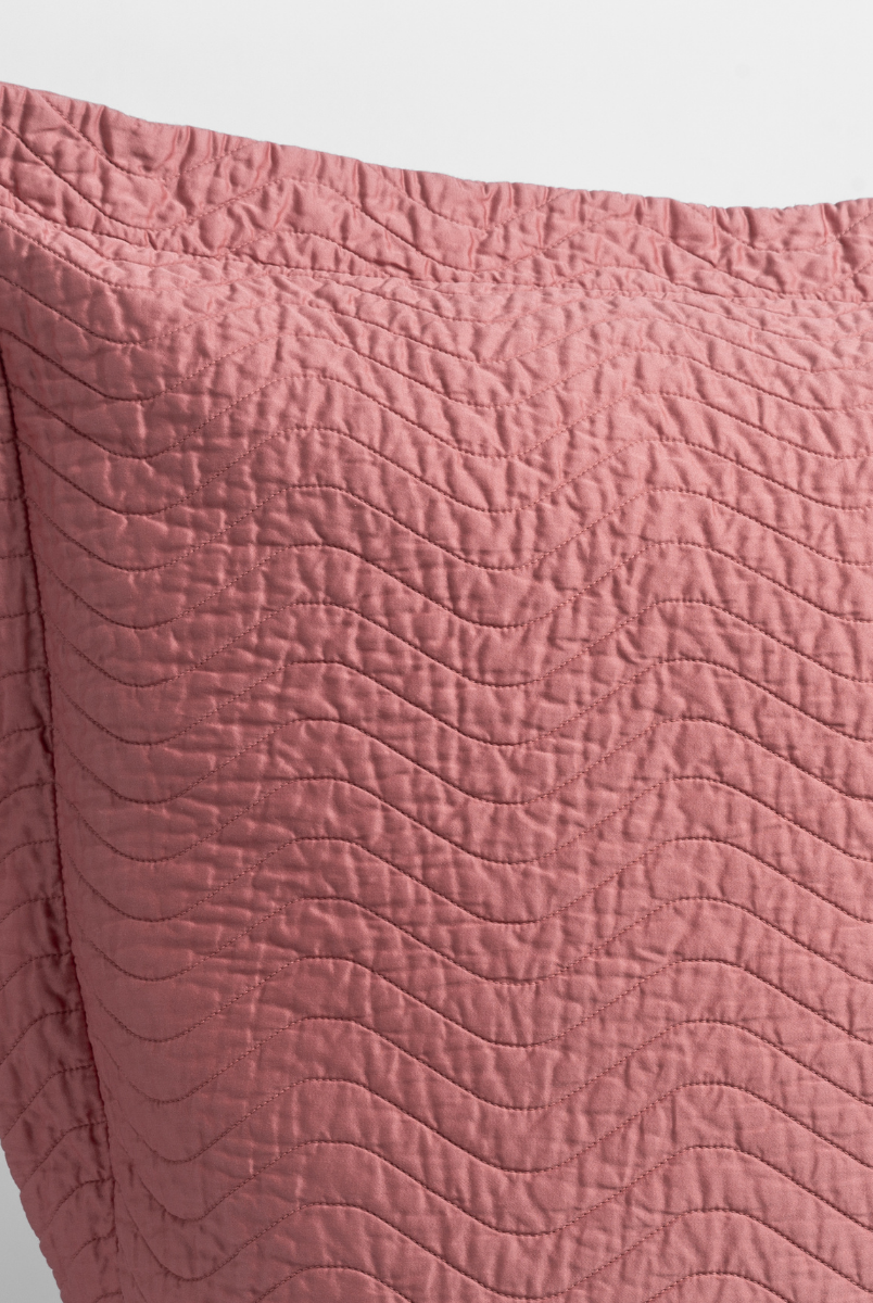 Poppy: a close up of a pillow corner showing the flange framing quilted cotton sateen shot against a white background. 