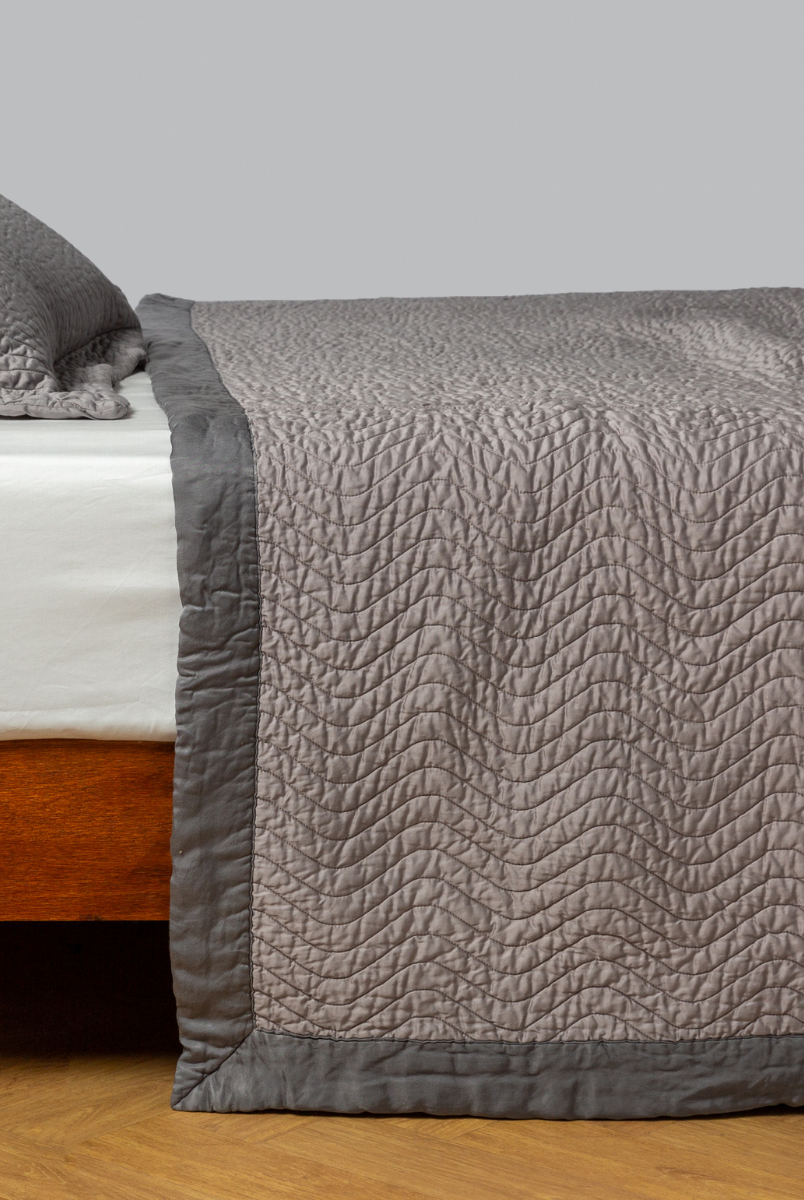 Fog: quilted cotton sateen coverlet with matching sham on a winter white fitted sheet - side view. 