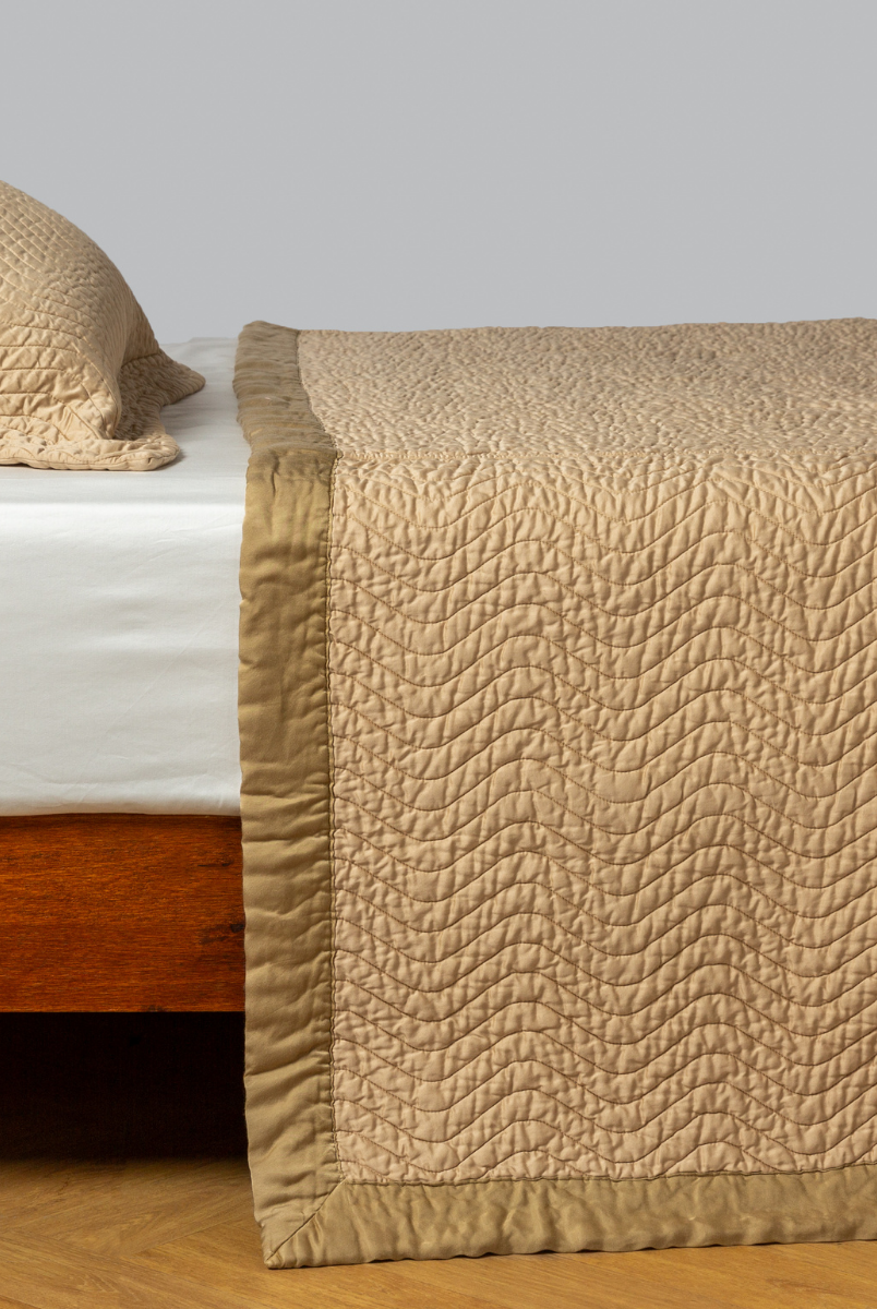 Honeycomb: quilted cotton sateen coverlet with matching sham on a winter white fitted sheet - side view. 