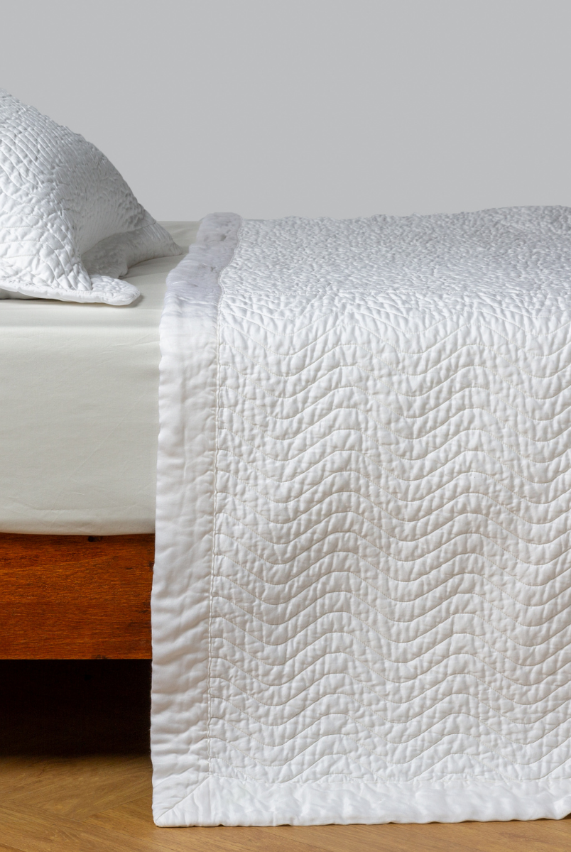 White: quilted cotton sateen coverlet with matching sham on a winter white fitted sheet - side view. 