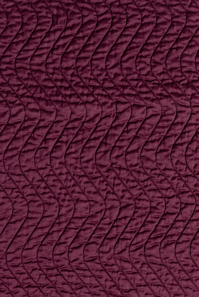 Fig: A close up of quilted cotton sateen fabric in fig, a richly saturated purple-garnet.
