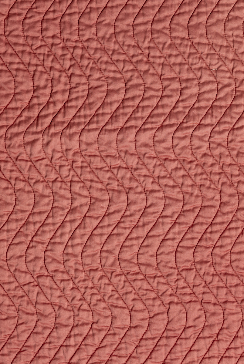Poppy: A close up of quilted cotton sateen fabric in poppy, a warm coral pink.