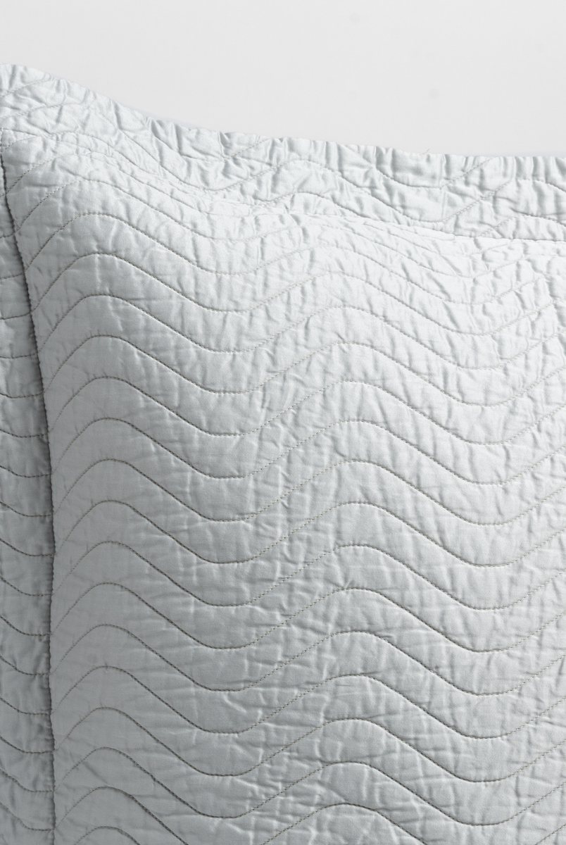 Cloud: close up of the corner of a quilted cotton sateen pillow sham - shot against a white background. 
