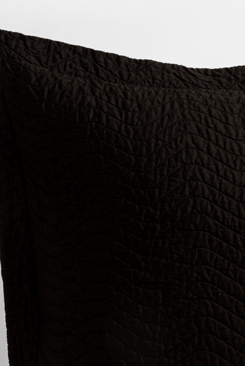 Corvino: close up of the corner of a quilted cotton sateen pillow sham - shot against a white background. 