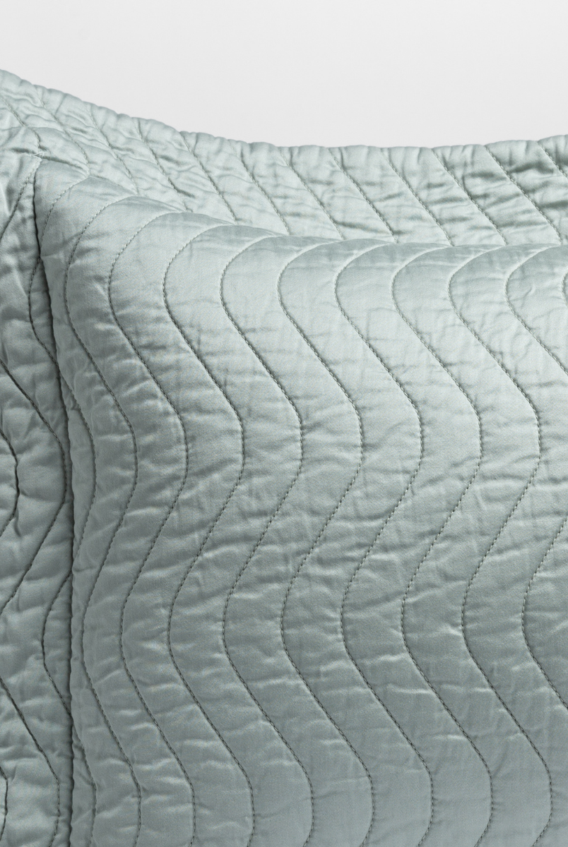 Eucalyptus: close up of the corner of a quilted cotton sateen pillow sham - shot against a white background. 