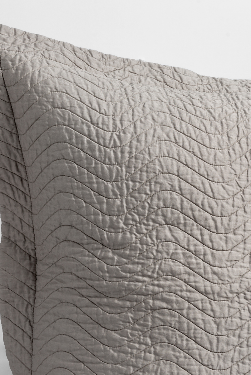 Fog: close up of the corner of a quilted cotton sateen pillow sham - shot against a white background. 