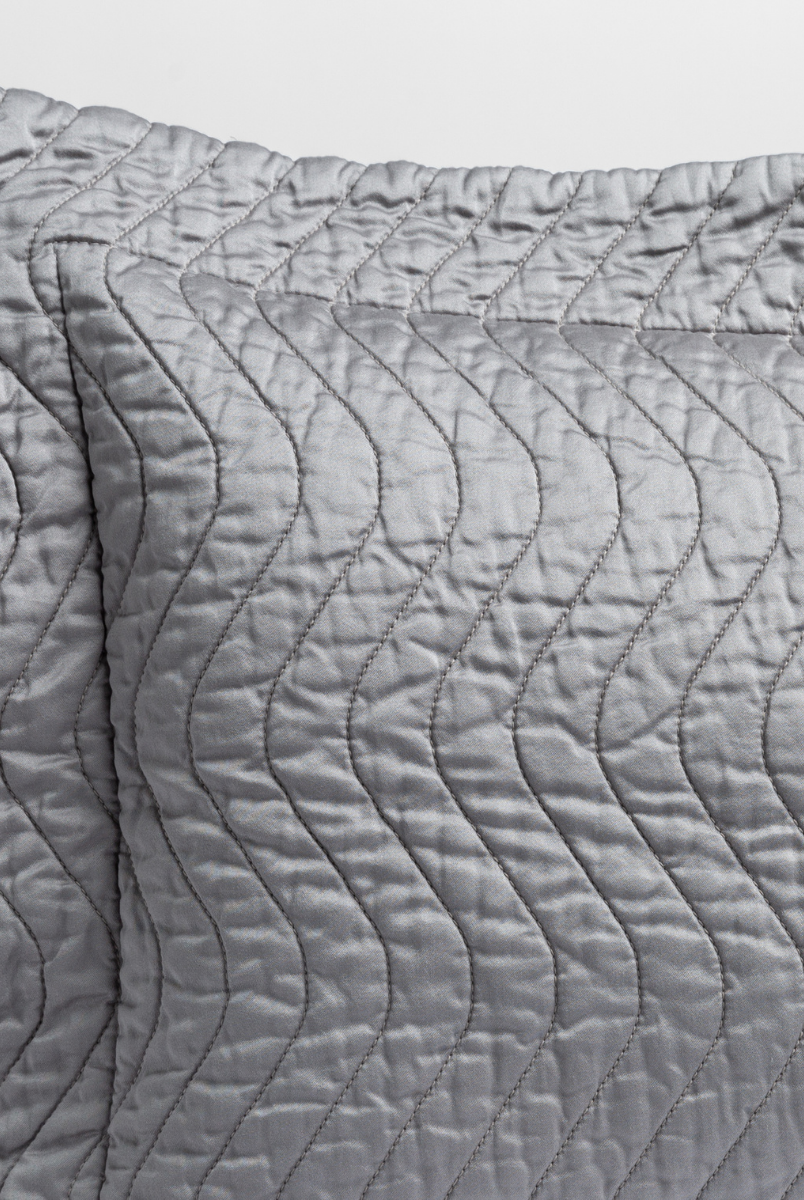 Moonlight: a close up of a pillow corner showing the flange framing quilted cotton sateen shot against a white background. 