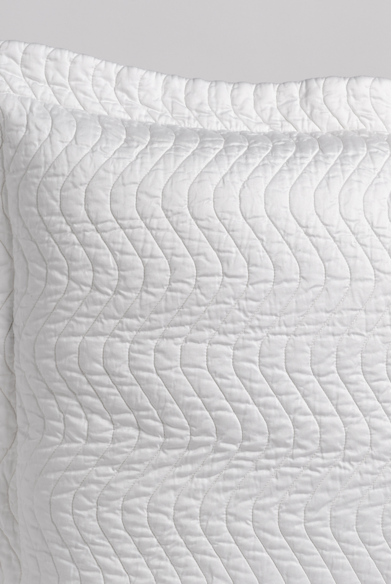 White: close up of the corner of a quilted cotton sateen pillow sham - shot against a white background. 